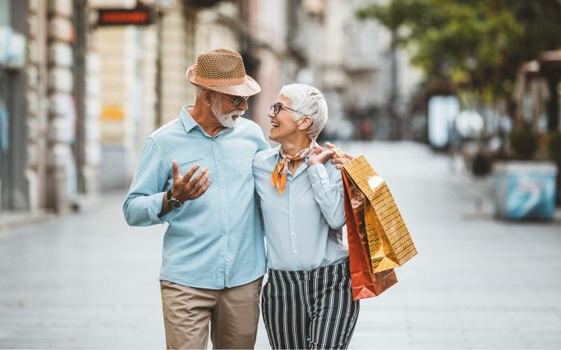 a man and woman holding shopping bags while walking